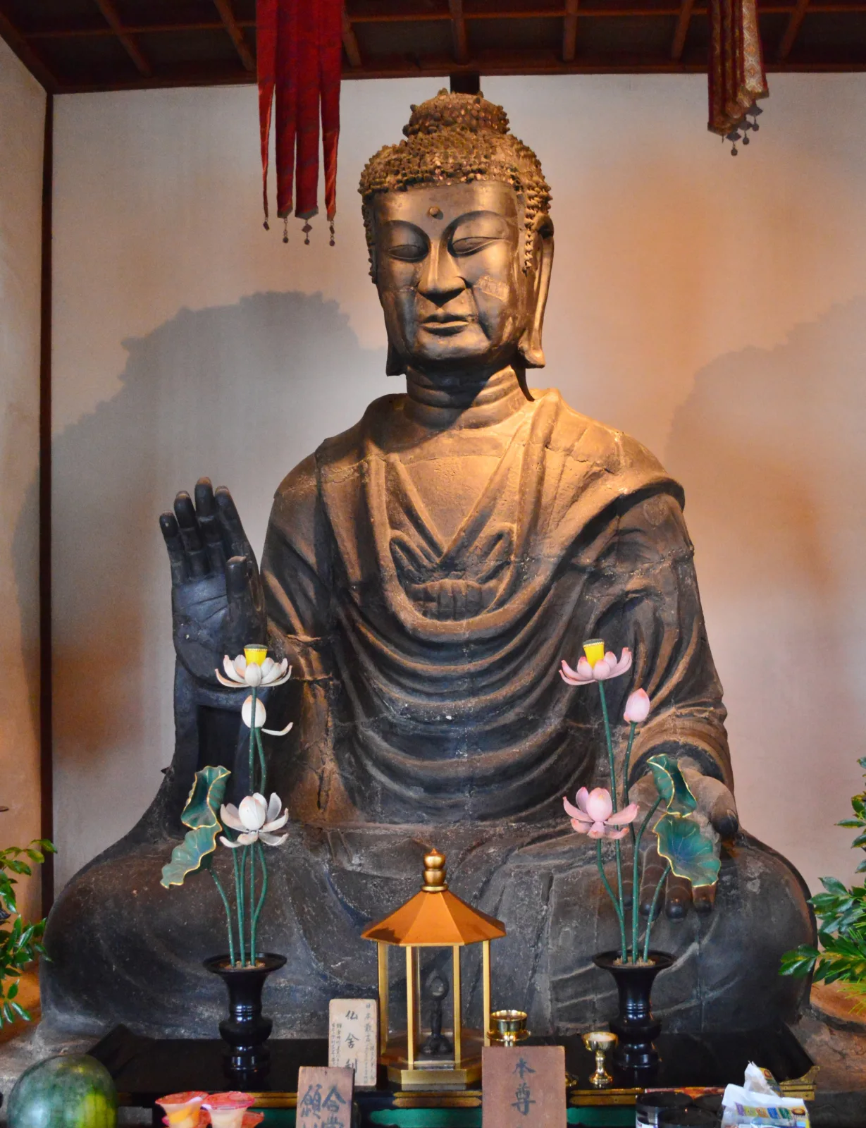 飛鳥寺釋迦如來全身正面實拍,端坐,右手抬起,身前有蓮花供燈